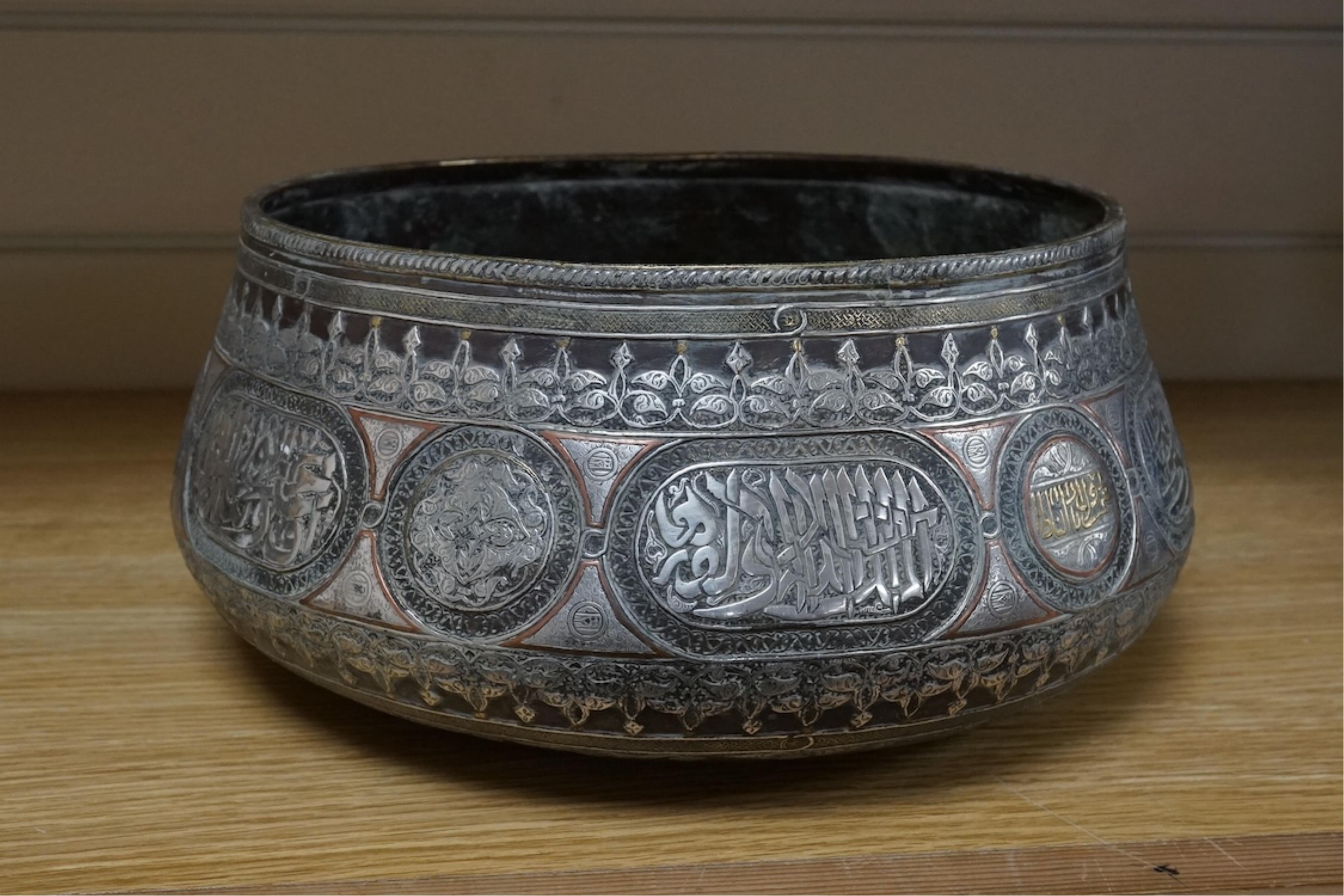 A late 19th century Mamluk style brass basin inlaid with silver and copper decoration, 29cm diameter